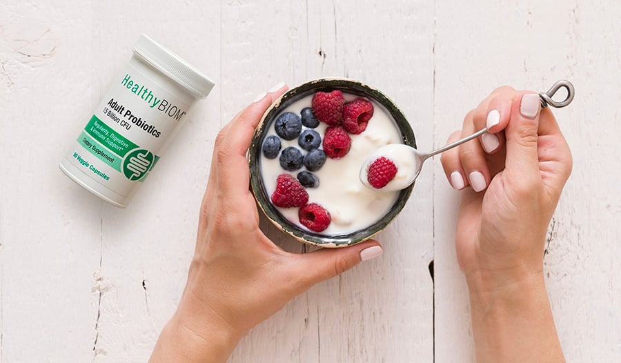 Healthy yogurt with berries in a bowl on a table with bottle of probiotics