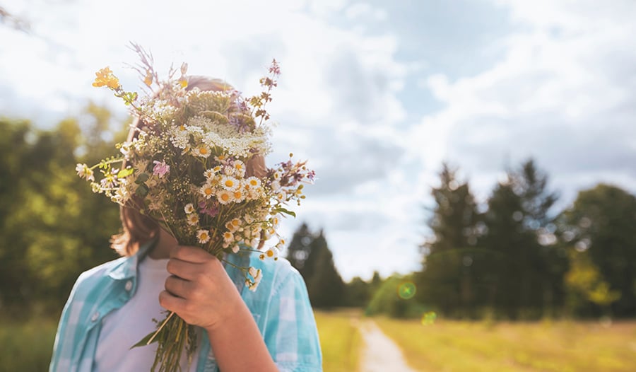 Child holding bouquet of flowers outside in nature