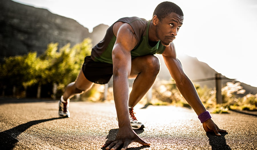 Athletic male getting ready to run outside in sprinting position