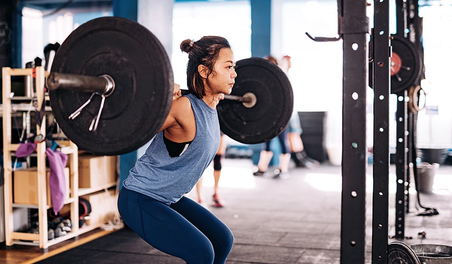 Asian woman with barbell lifting weights in the gym