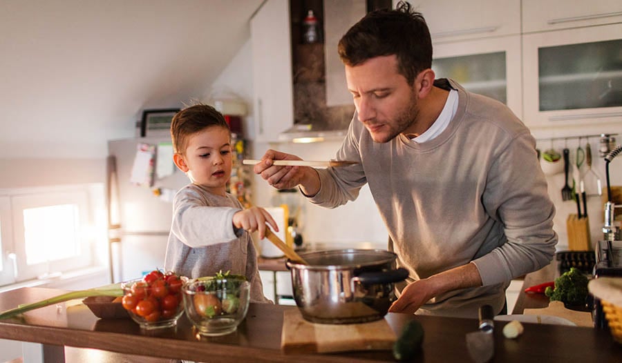 Father making soup in kitchen with son