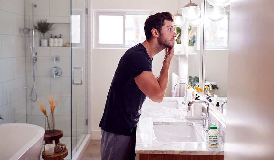 Man standing in bathroom looking in mirror