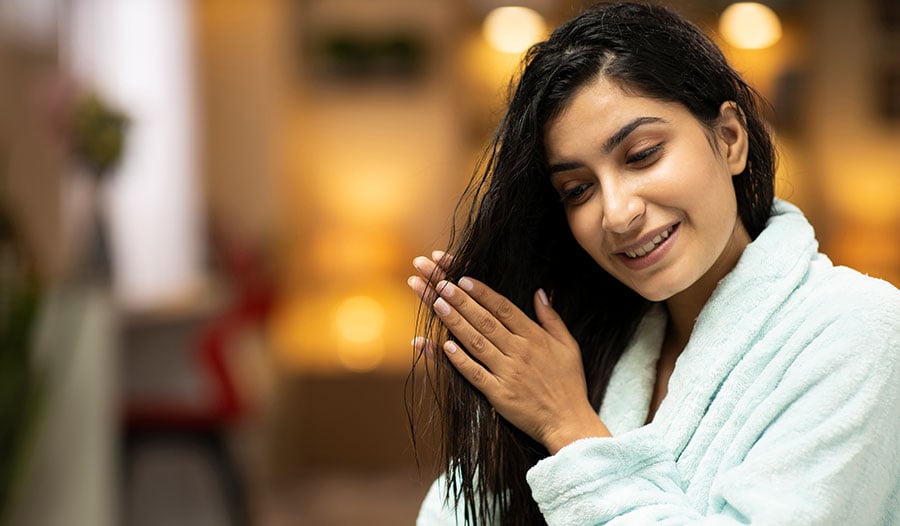 woman applying hot oil as a hair treatment for soft and glossy hair