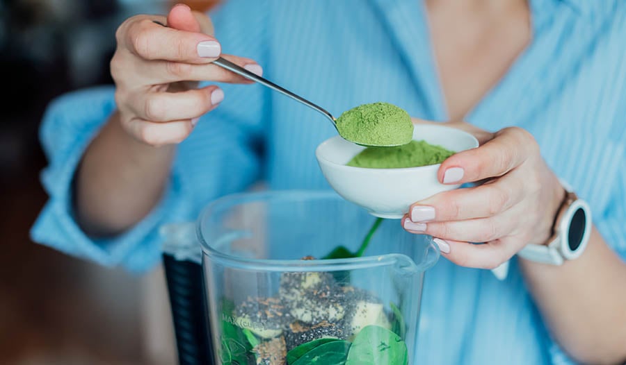 Woman making smoothie with super greens powder