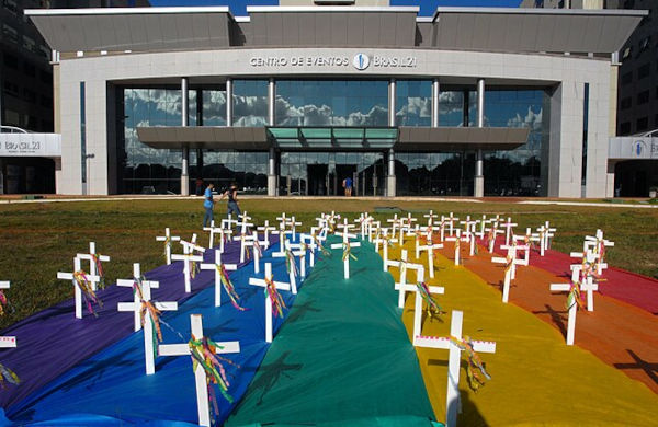 Cruzes sobre bandeira do movimento LGBTQIA+, em texto sobre violência doméstica.