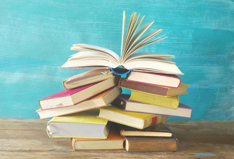 stack of books on a table, with open book on top