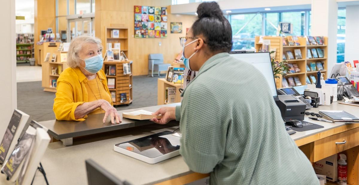 A librarian helps a patron