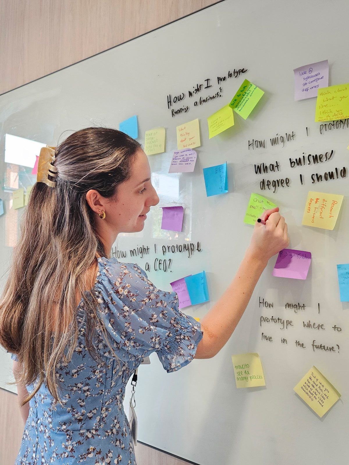 Student adding to the stick note wall of ideas