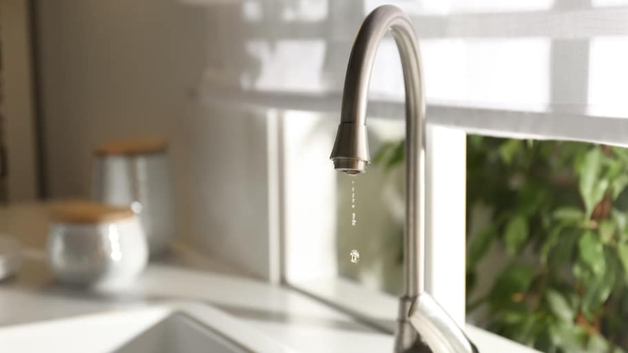 Water drops falling down from tap in kitchen