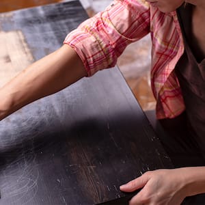 Woman resurfacing a black wooden table