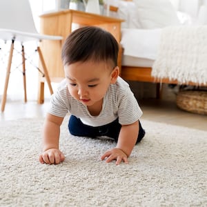 Baby boy crawling on carpet at home