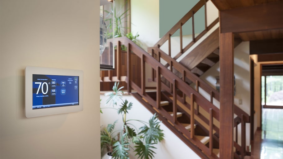 Digital thermostat mounted on the wall by the stairs