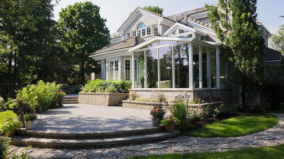 The exterior of a house with a sun room and a lush garden