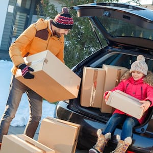 A father with his daughter loading a car with moving boxes