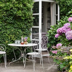 A garden with white wrought iron furniture