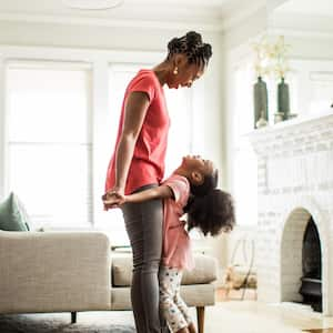 A girl standing on mothers feet