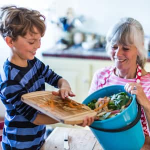 A grandson helping his grandmother with kitchen waste for composting