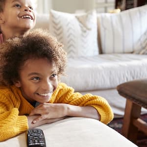 Two kids watching tv on couch