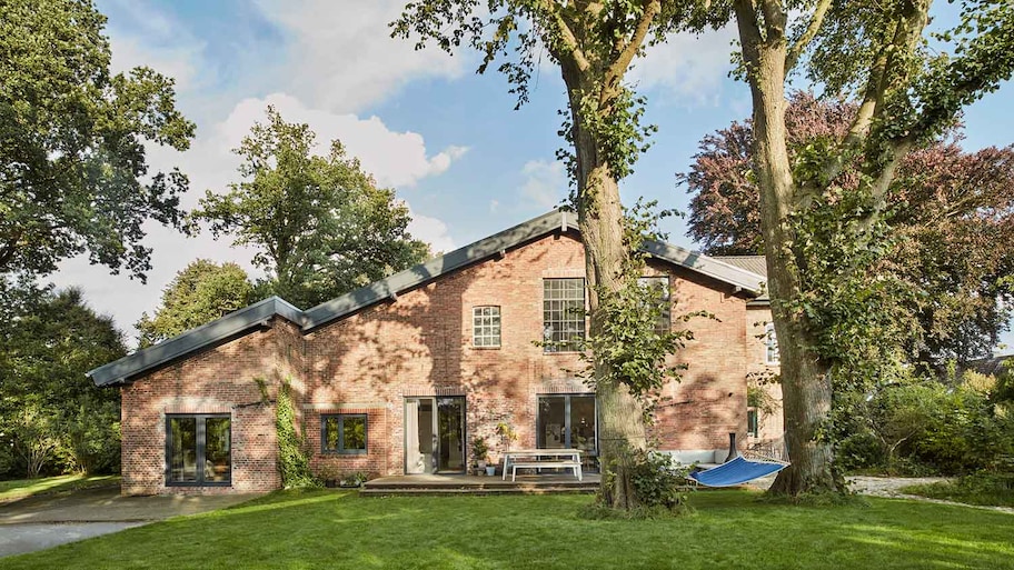 Large brick house surrounded by tall trees