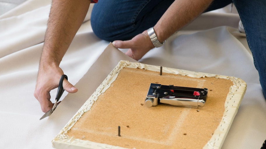 A man cutting a piece of fabric with scissors