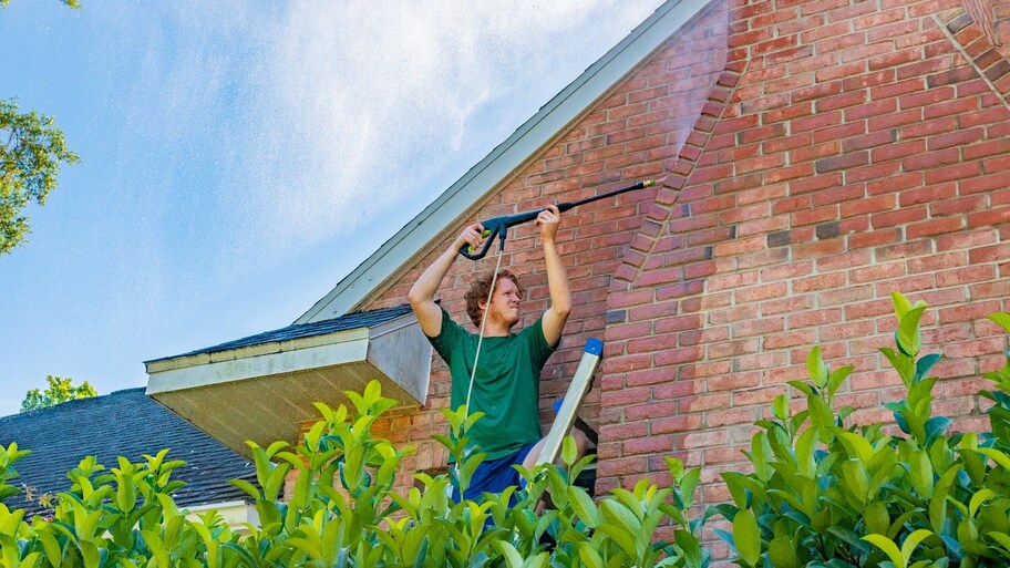 A man pressure washing the exterior of his house