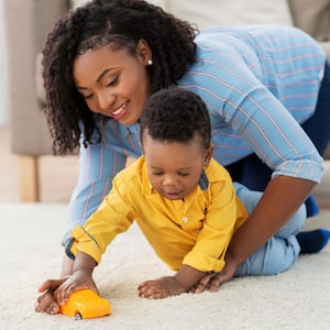 Mother and toddler son playing on the carpet