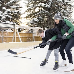 mother and son playing ice hockey in yard