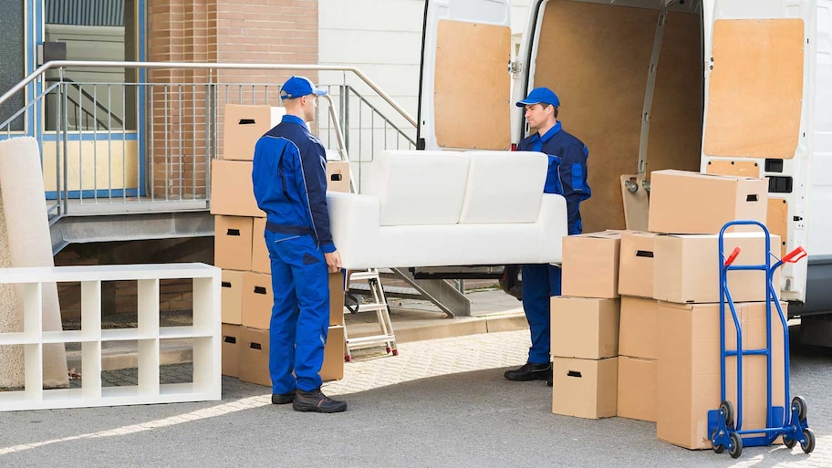 Professional movers carrying sofa into a truck