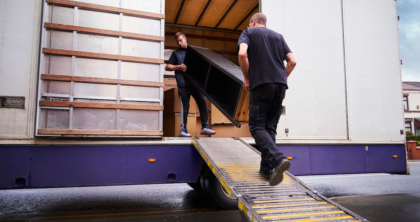 Employees of a moving company loading with furniture a truck