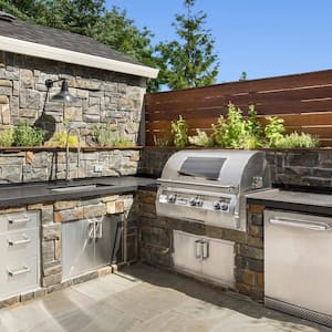 A stone outdoor kitchen with a built-in grill