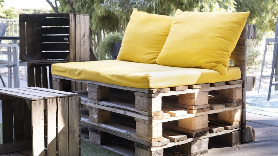 A pallet bench with a yellow cushion