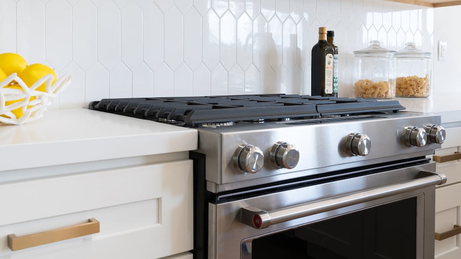 A patterned white tile backsplash in front of the stove