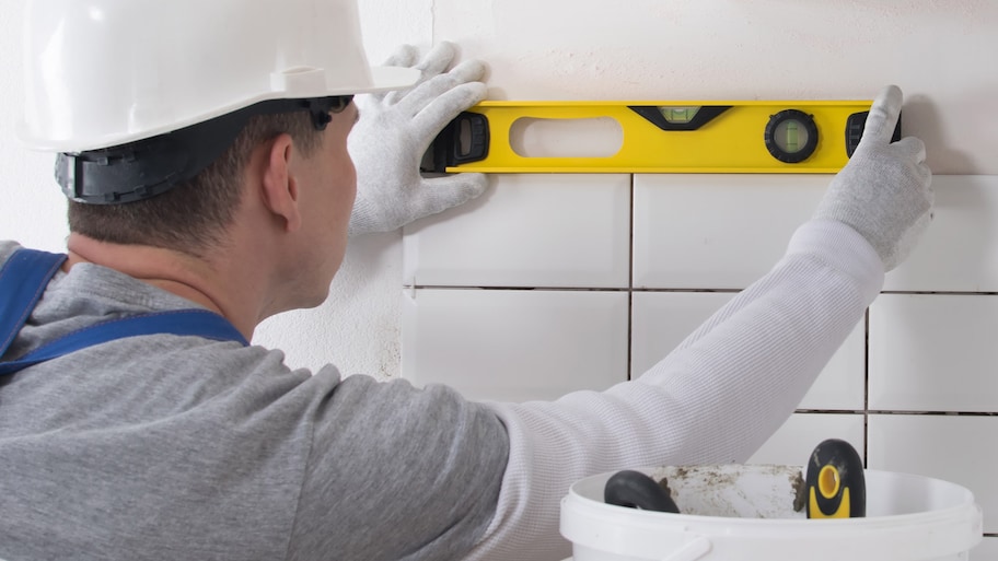 A professional using a level while installing tiles