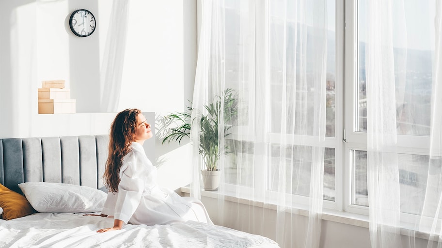 Woman in white bathrobe sitting on bed