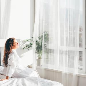 Woman in white bathrobe sitting on bed