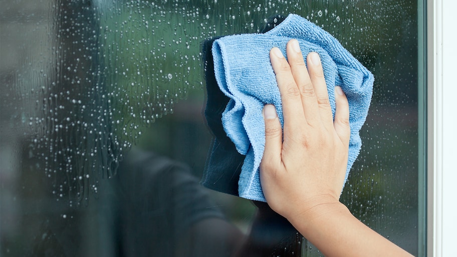 woman cleaning window with rag