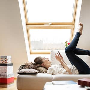 A woman relaxing in an attic with an egress window shining light