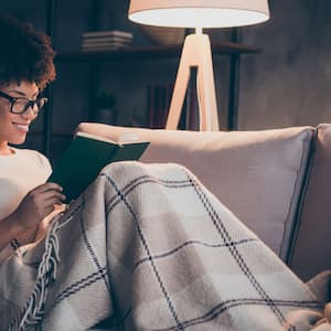 A woman covered in a blanket reading a book