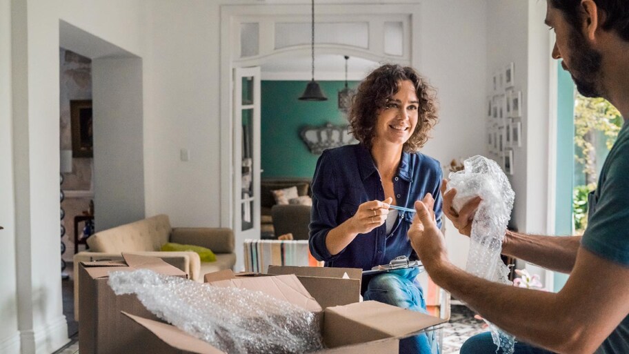 A happy woman with spouse packing cardboard boxes