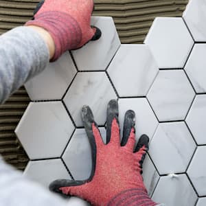 A worker laying tiles on a wall