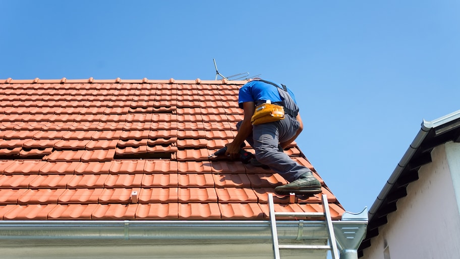 Worker repairing roof shingles