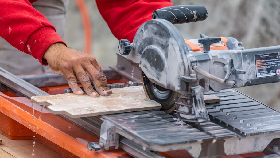 A worker using a wet tile saw to cut tiles