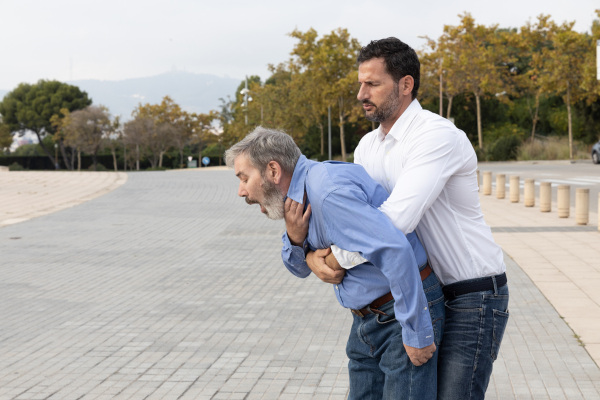 Homem realizando a manobra de Heimlich em um idoso.