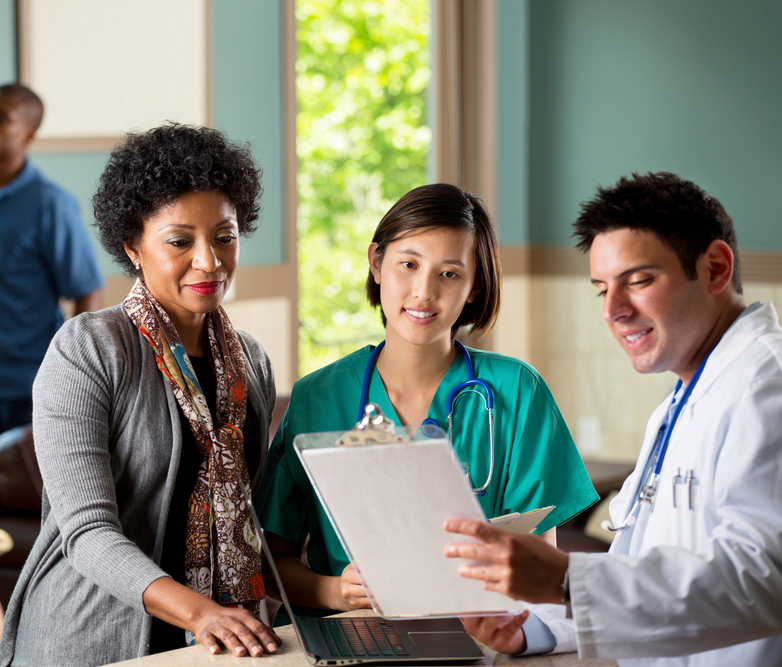 Doctor holding a clipboard with two women