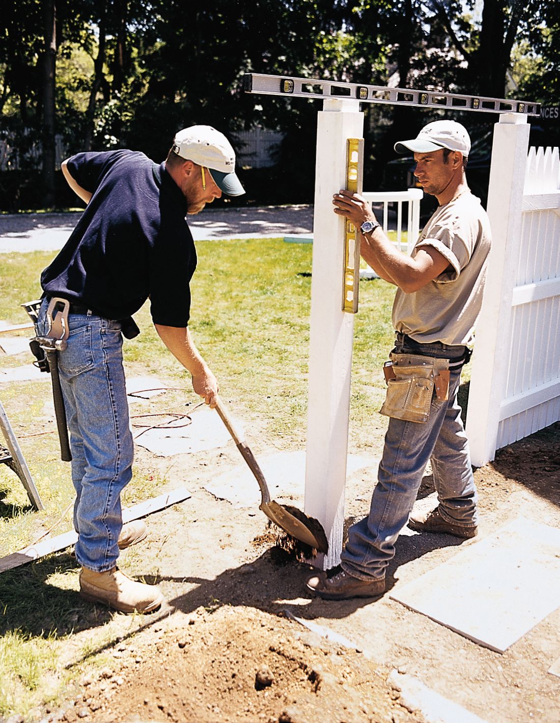 two people setting a post into the hole and covering it with dirt