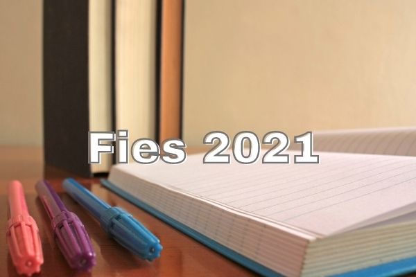 Estudante sorrindo ao lado do texto “Fies 2024”, que está sobre outros estudantes ao fundo da imagem.