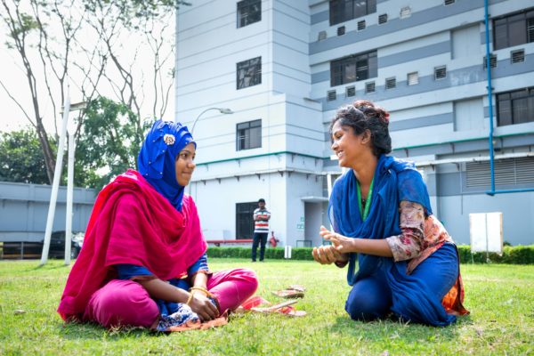 photo of women sitting on grass talking