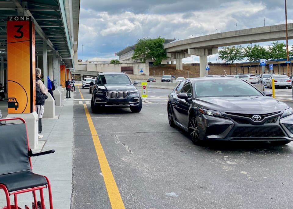 Two cars are stopped at Zone 3 of the Rideshare pick up area.