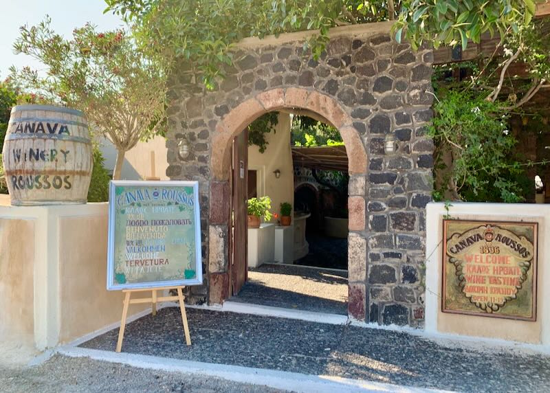 Rustic stone doorway, overhung with vines and with winery signage