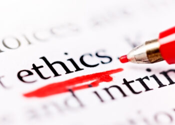 A red felt-tipped pen underscores the word "ethics" on a printed page.